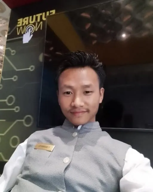 Young man in a hospitality uniform smiling at his workplace