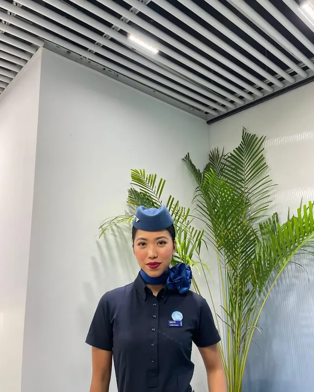 Young woman in an airline-style uniform standing in a modern lobby