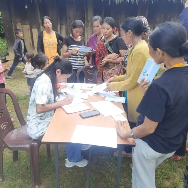 Women filling in forms at a table during an outdoor registration camp