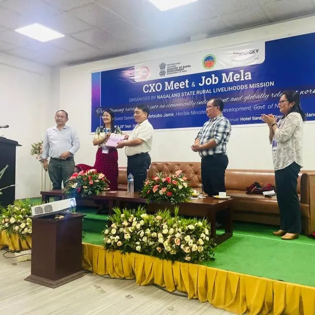 Speakers on stage at the CXO Meet and Job Mela, decorated with flowers