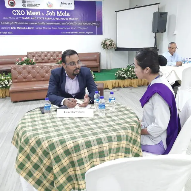 Recruiter interviewing a young candidate at a table during the Job Mela