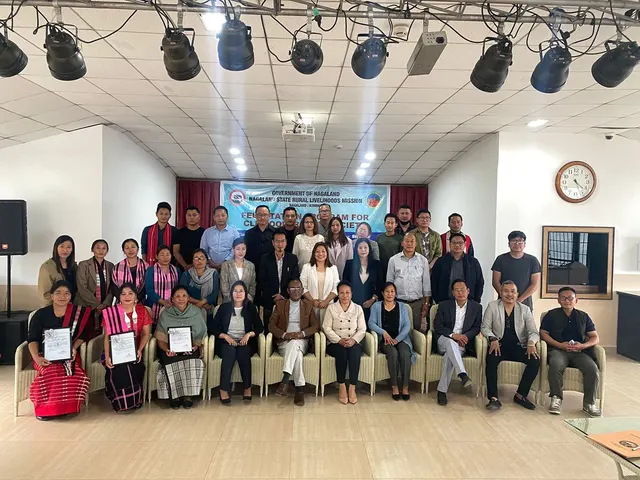 Group photo of trainees and officials holding certificates in an auditorium